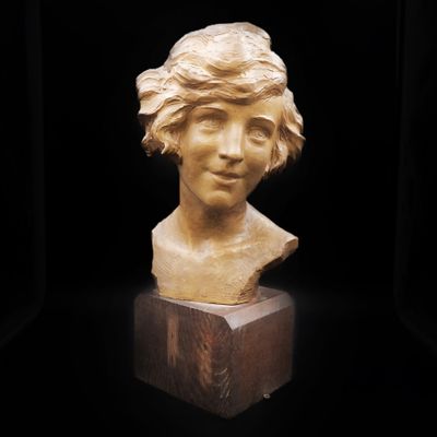 un gros plan sur une sculpture représentant une tête de femme posée sur un bloc de bois
