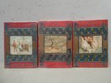 trois livres rouges sur lesquels figurent des photos de personnes, posés sur une surface blanche