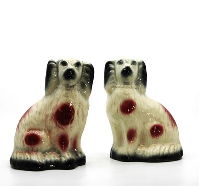 deux chiens en céramique assis l'un à côté de l'autre sur une surface blanche