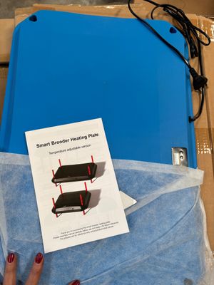 a person holding a blue box with a sheet of paper on top of it