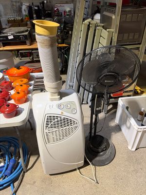 une pièce avec un ventilateur, une table et d'autres objets posés par terre