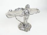 a silver figurine of a woman holding a leaf