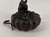 une petite statue représentant un chat assis sur une citrouille