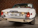 a white car that is parked in front of a brick wall
