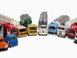 Plusieurs camions miniatures sont alignés en cercle sur une surface blanche