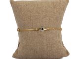 le bracelet en chaîne d'or est posé sur un coussin, sur un fond blanc