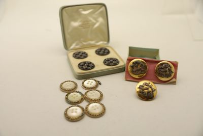une boîte de boutons et une paire de boucles d'oreilles posées sur une table