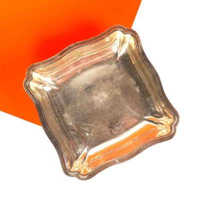 une assiette en argent posée sur une table orange et blanche