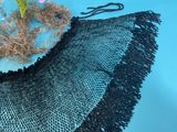 a black crocheted shawl on a blue table