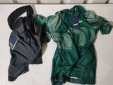 a green jacket and black pants laying on the floor