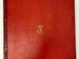 an old red book with a gold monogram on the cover