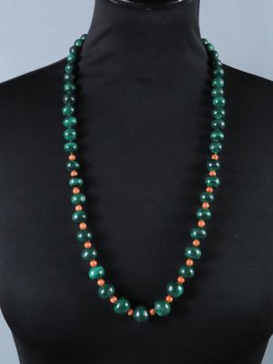 un collier de perles vertes et orange sur un mannequin