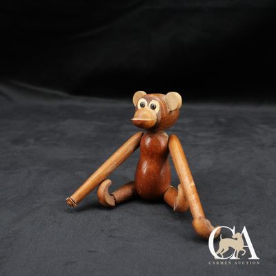singe en bois assis par terre, une batte de baseball à la main