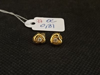 une paire de boucles d'oreilles en or et diamants sur une surface noire