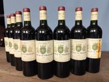 six bottles of wine are lined up on a wooden table
