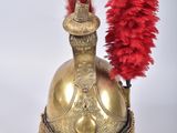 gold helmet with red feathers on top of it on a white surface