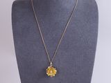 a gold necklace with a flower pendant on a mannequin