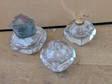 trois bougeoirs en verre posés sur un plancher en bois