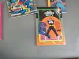 many comic books on a table with a pink bag