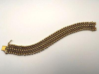 gros plan d'un bracelet en or sur une surface blanche