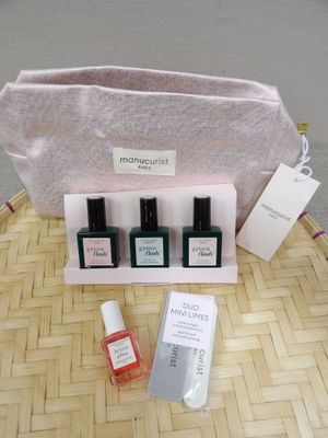 trois flacons de vernis à ongles et un sac posés sur une table