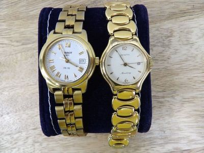 pair of ladies ' s wrist watches with gold tone bracelets on display