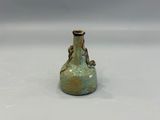 un petit vase vert posé sur une surface blanche