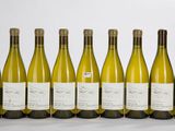 six bouteilles de vin blanc alignées sur une surface blanche