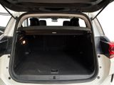 the back of a white car with its trunk open and the back seats folded down