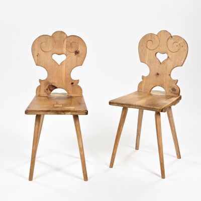 une paire de chaises en bois ornées de cœurs sculptés sur fond blanc