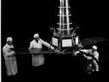 photographie en noir et blanc représentant un groupe d'hommes travaillant sur une maquette de station spatiale