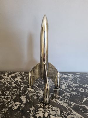 une image représentant un objet argenté en forme de fusée posé sur une surface en marbre