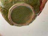 a person holding a green vase with writing on it