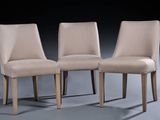 three beige chairs sitting next to each other in a dark room