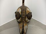 a wooden mask on the floor in a room