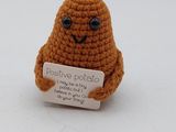une petite peluche qui tient une pancarte