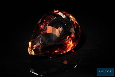 un gros plan d'un gros diamant orange sur une surface noire