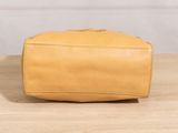 a tan leather toilet bag sitting on top of a wooden table