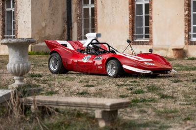 une voiture de course rouge garée devant un immeuble