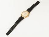 a gold wrist watch with a black leather strap
