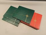 several green and red books stacked on top of each other on a table