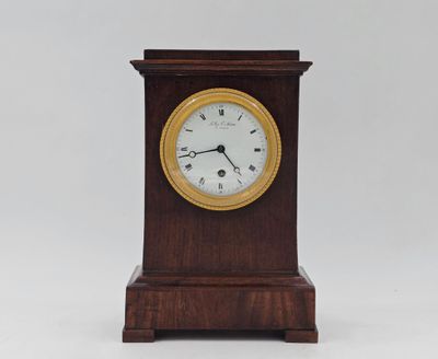 une petite horloge en bois avec un cadran blanc sur fond blanc