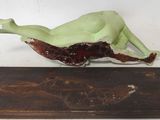 a figurine of a woman laying on a wooden base