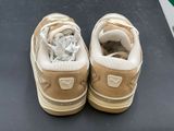 pair of tan sneakers with white laces on a black surface