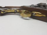 a close up of a rifle with a brass handle on a white surface