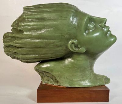 une sculpture verte représentant la tête d'une femme, posée sur un socle en bois