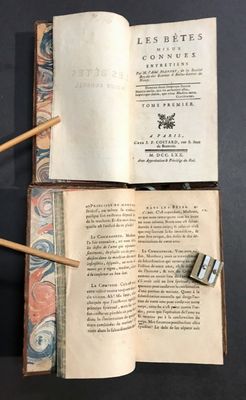 un livre ouvert, d'où sortent des bâtonnets en bois, posé sur une table