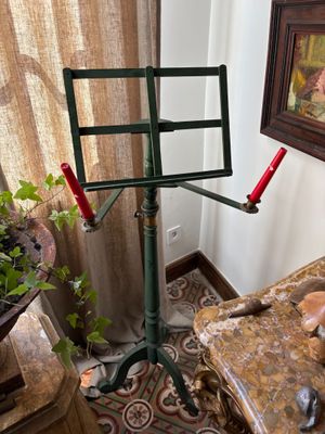 a music stand in the corner of a room with a painting on the wall