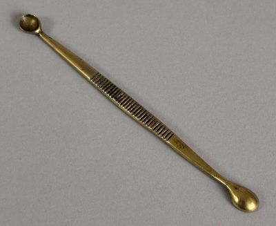 a gold spoon and a spoon rest on a white surface