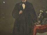 portrait of a man in a tuxedo and bow tie standing in front of a table with a vase of flowers